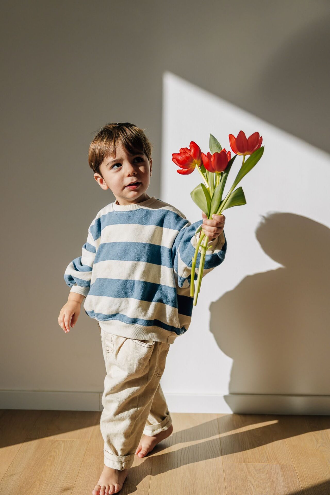 petit garçon avec un bouquet de tulipe dans une lumière graphique lors d'une séance photo à domicile à Aix-en-Provence