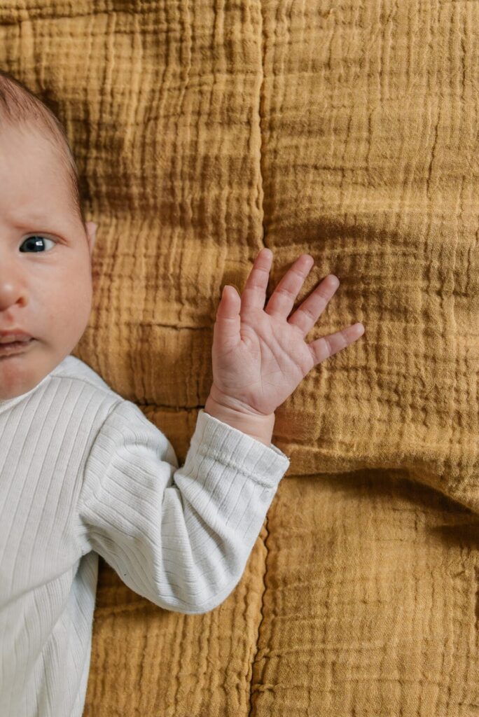 Portrait d’un bébé allongé sur une couverture jaune lors d’une séance photo bébé à domicile à Marseille