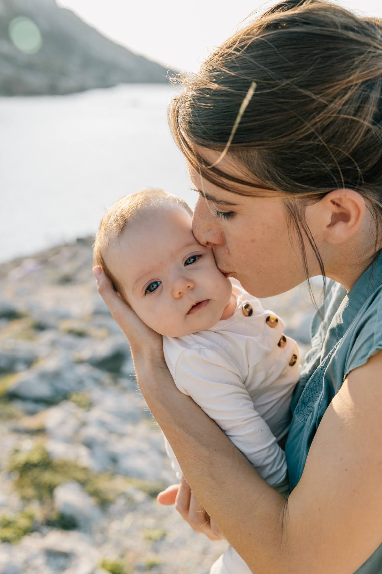 Maman embrassant son bébé en bord de mer lors d’une séance photo bébé dans les calanques à Marseille