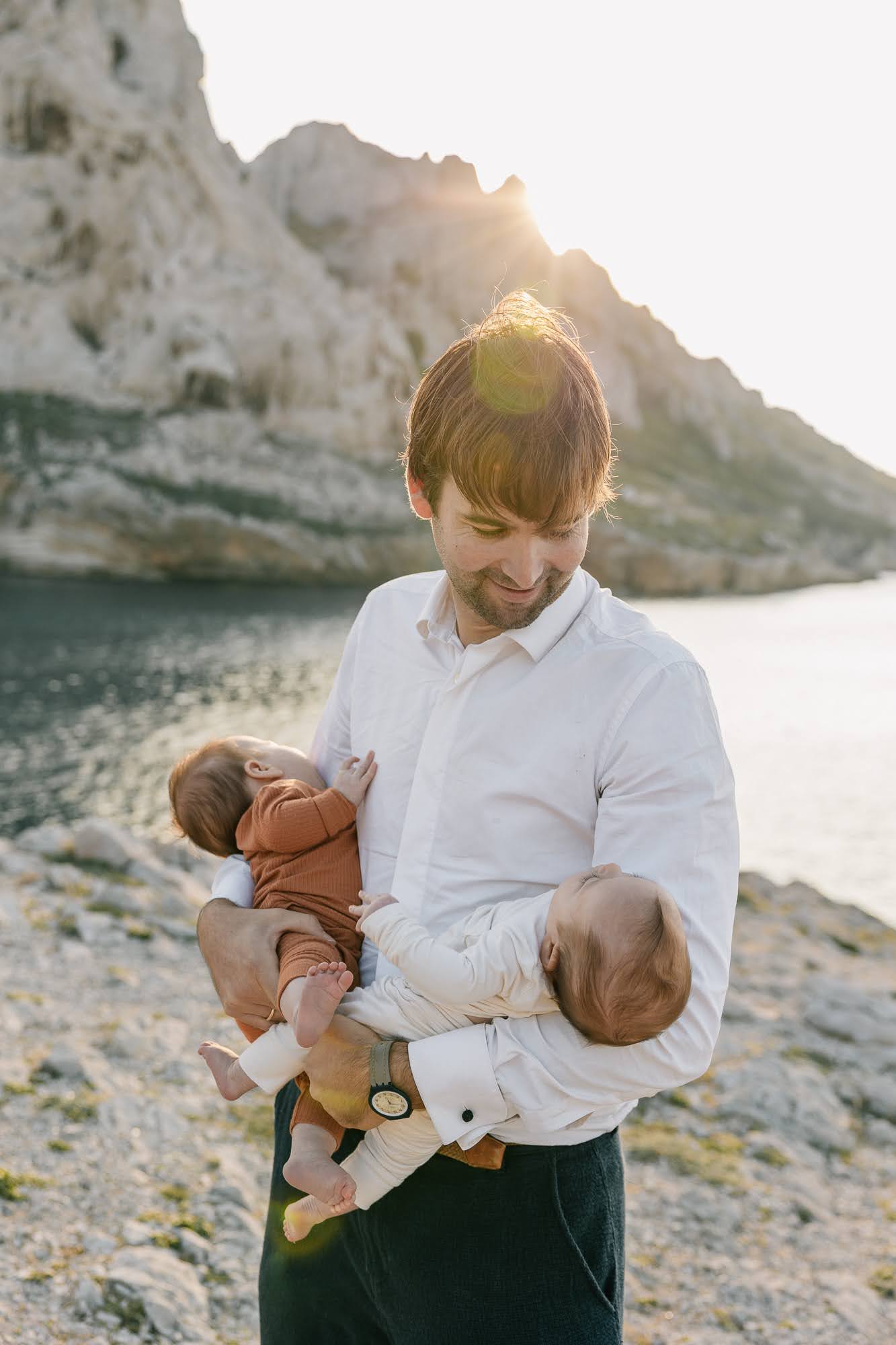 Père portant ses bébés en bord de mer lors d’une séance photo famille aux Goudes à Marseille