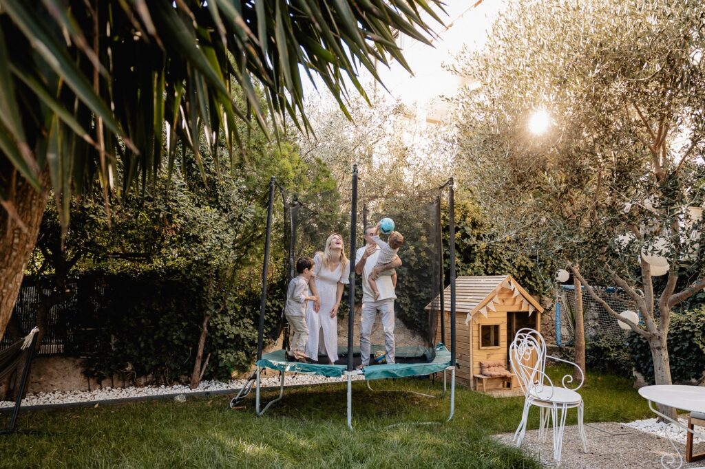 Enfants qui jouent sur un trampoline dans un jardin à Marseille, lors d’une séance photo famille.