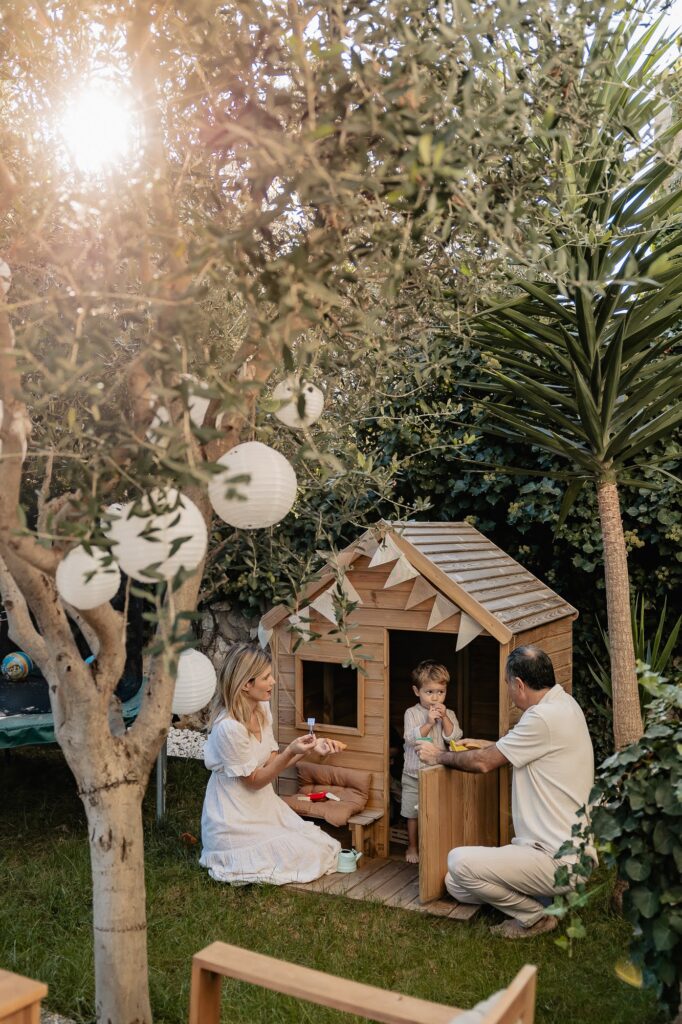 Enfants qui jouent dans une cabane en bois dans un jardin à Marseille, séance photo famille.