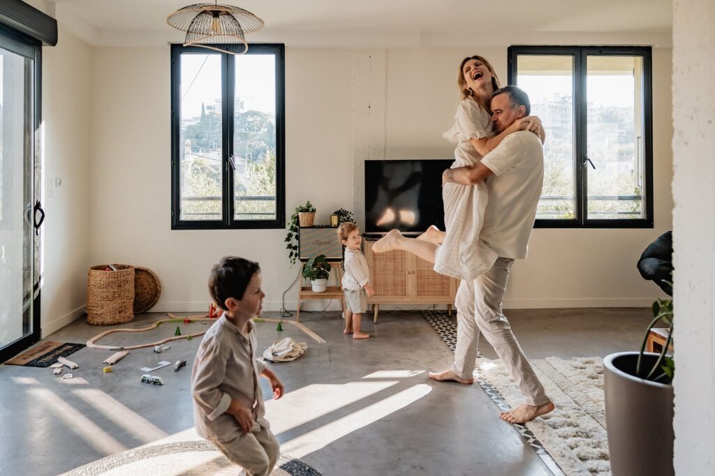 Parents qui dansent dans leur salon, séance photo famille à domicile à Marseille.