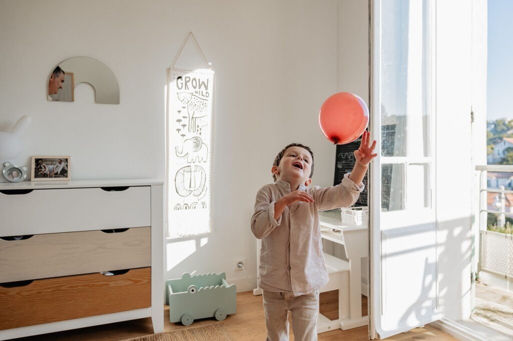 Enfant qui joue avec un ballon dans une chambre, séance photo famille à Marseille 13007.