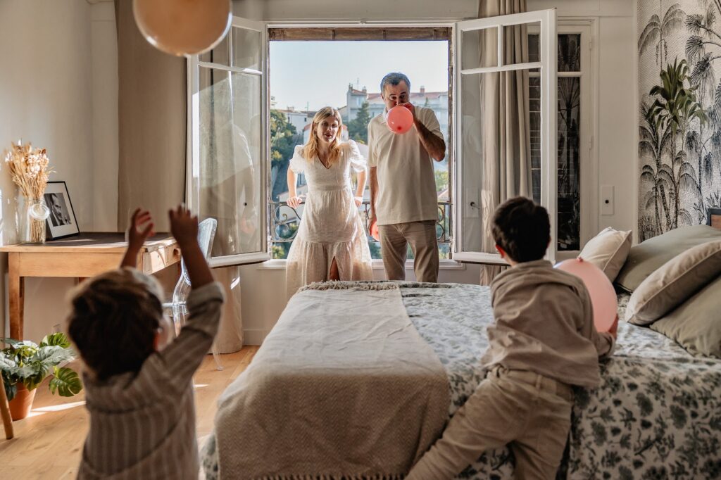 Famille à la fenêtre avec ballons, séance photo au Roucas-Blanc à Marseille avec vue dégagée.