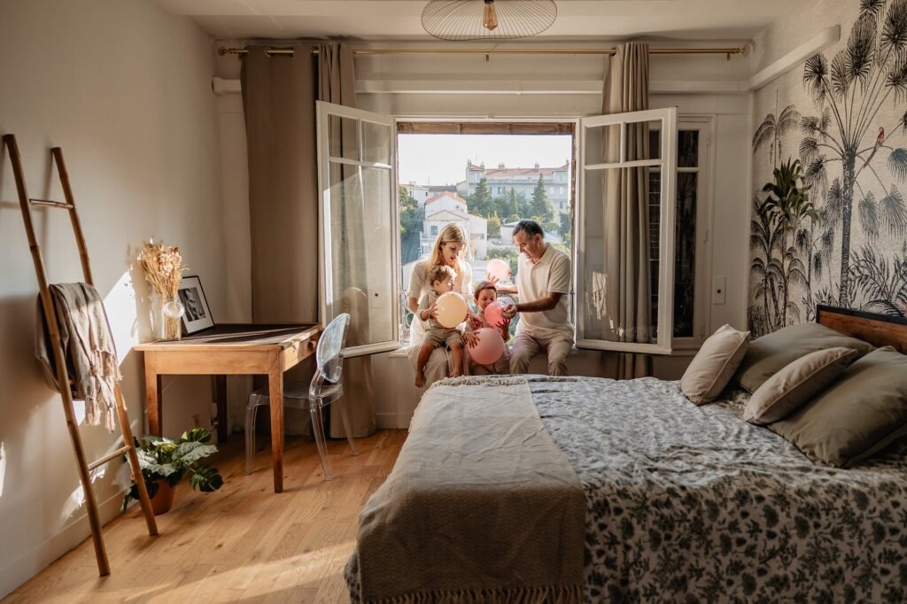 Séance photo famille dans une chambre lumineuse au Roucas-Blanc à Marseille, avec vue sur Notre-Dame.