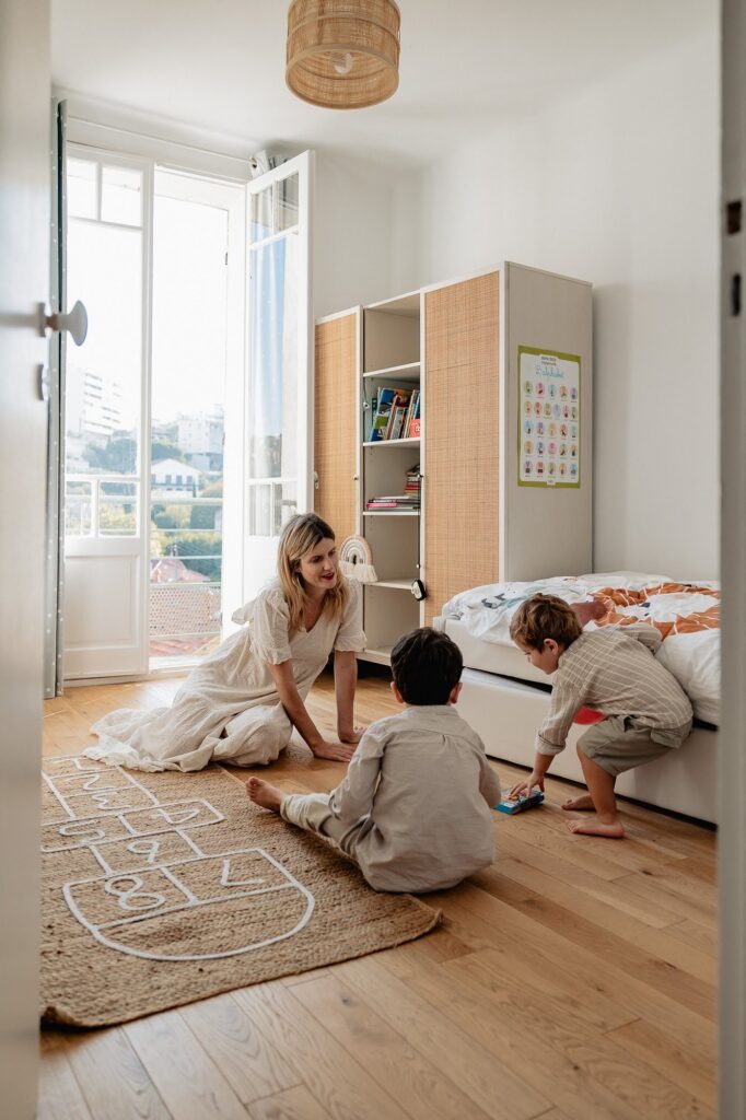 Enfants qui jouent dans une chambre lumineuse à Marseille 13007, séance photo famille à domicile.