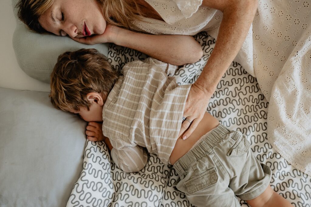 Mère et enfant allongés sur un lit, moment calme photographié à domicile à Marseille.