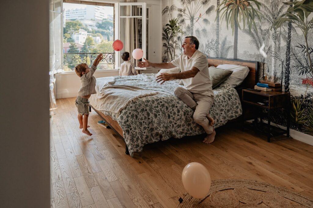 Famille assise à la fenêtre avec ballons, séance photo famille à Marseille dans le 7e arrondissement.