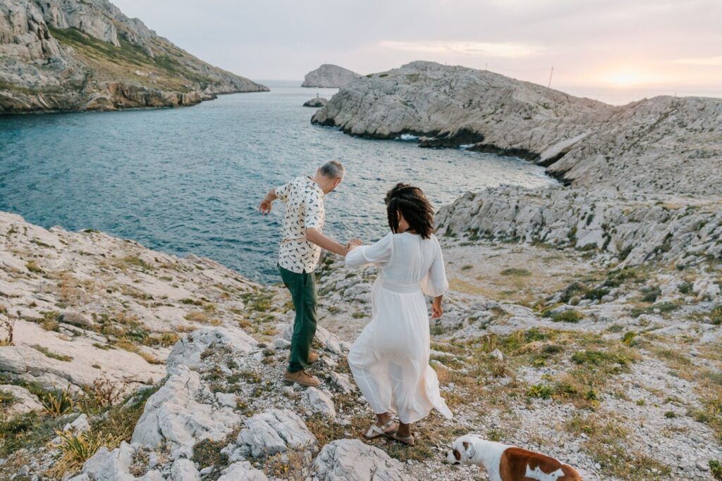 couple descendant les rochers des Goudes pendant une séance photo grossesse à Marseille