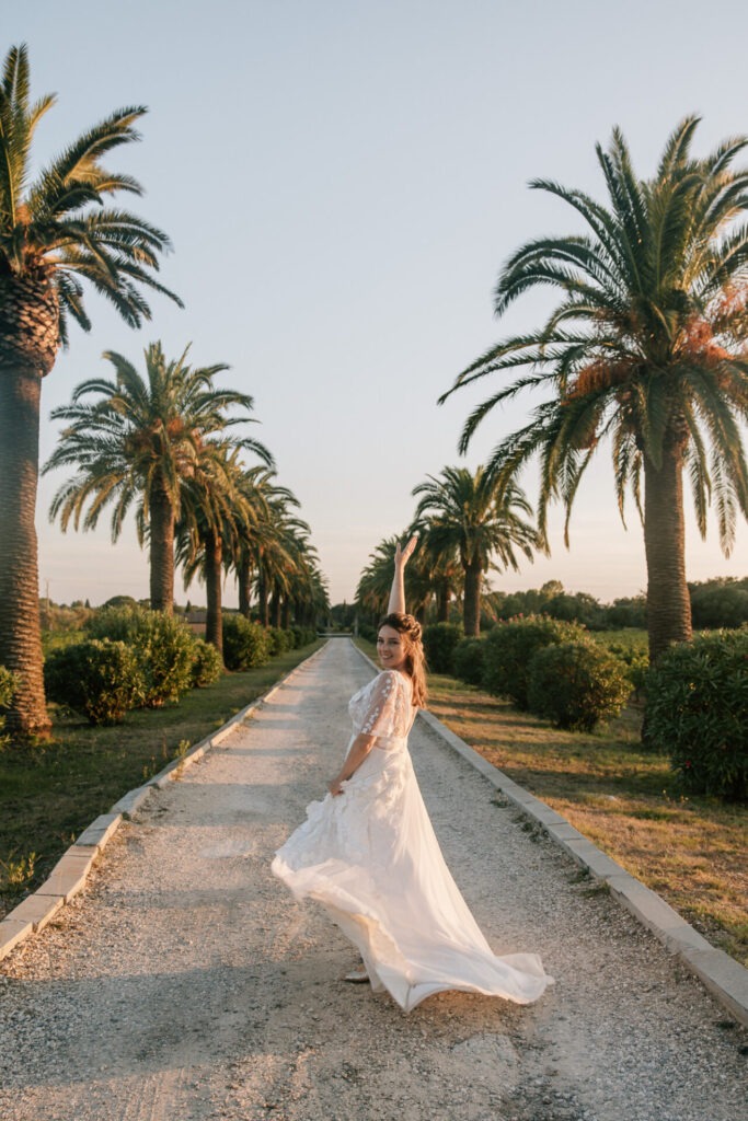 Mariée dans l’allée de palmiers du Château des Anglades à Hyères en Provence