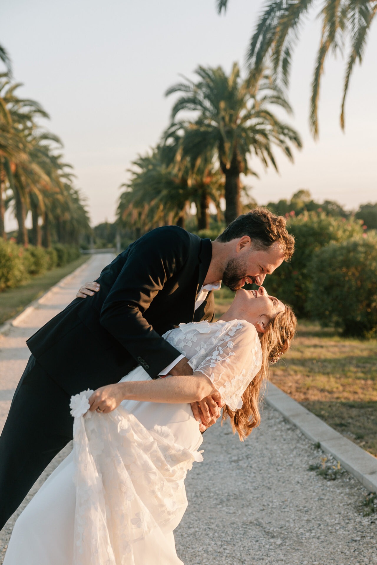 Portrait des mariés dans l’allée de palmiers du Château des Anglades à Hyères au coucher du soleil