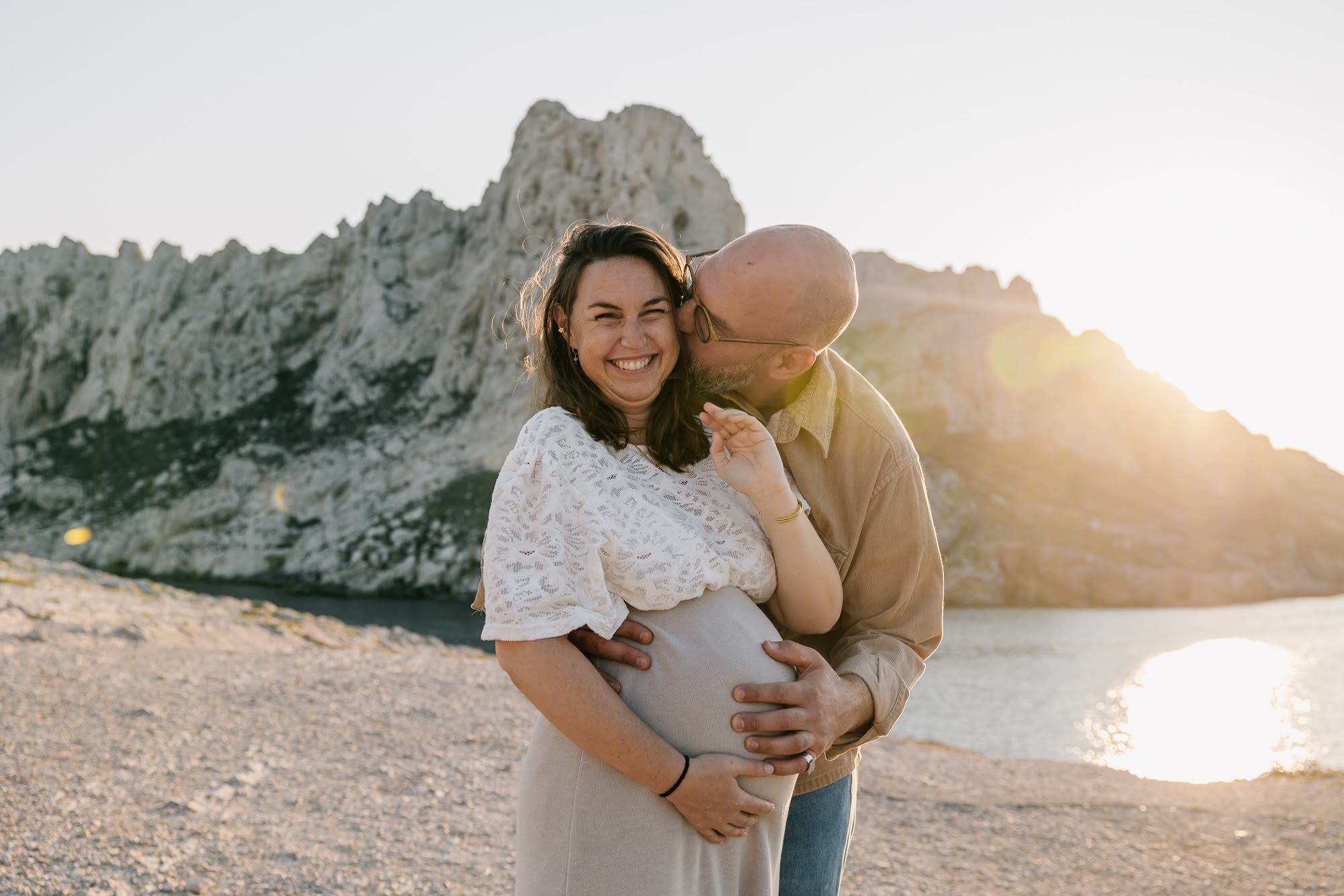 couple souriant au bord de la mer pendant une séance photo grossesse