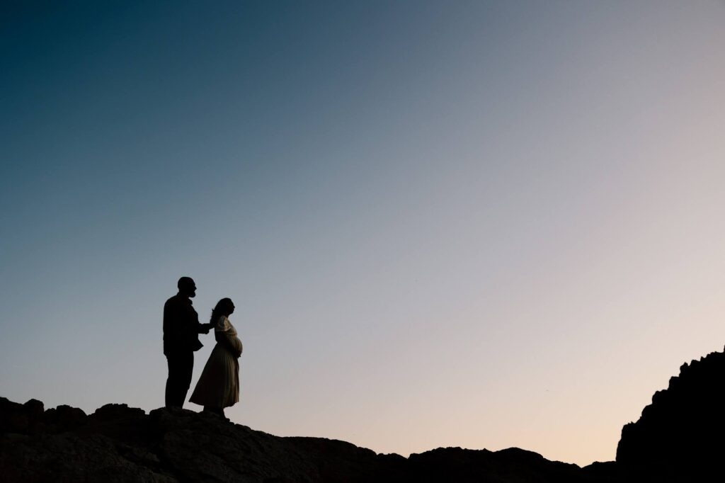 silhouette d'un couple lors d'une séance photo grossesse au coucher du soleil