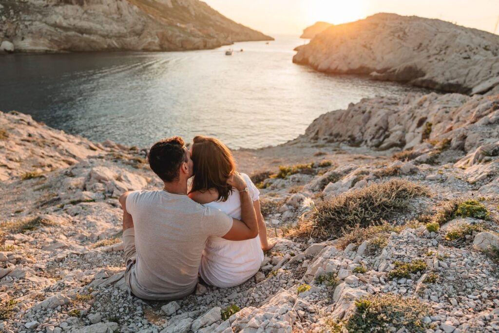 couple regardant la mer au coucher du soleil lors d'une séance photo grossesse aux Goudes