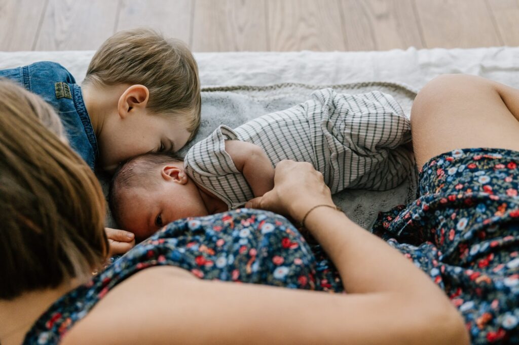 Maman et grand frère penchés tendrement sur le nouveau-né pendant l'allaitement