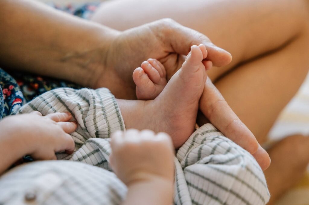 Détail des pieds du nouveau-né et des mains de la famille