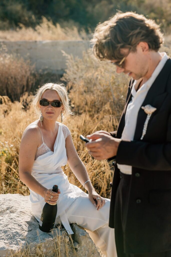 Mariée assise dans les calanques de Marseille avec une bouteille de champagne