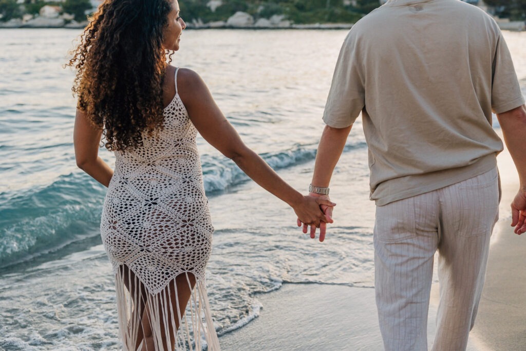couple se tenant la main pendant une séance grossesse à la plage