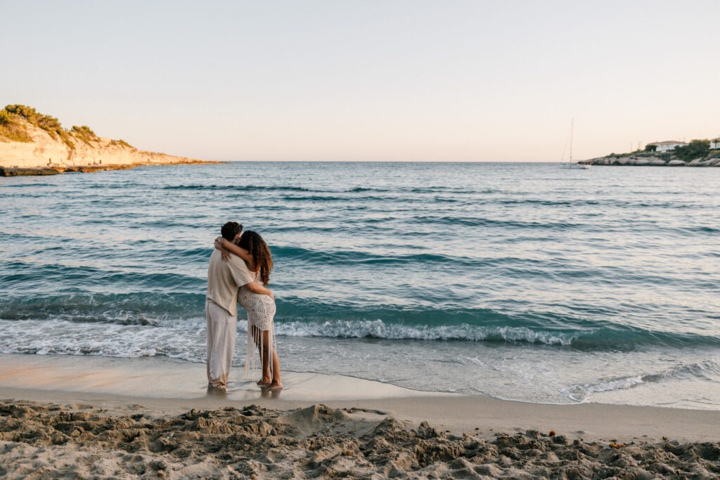 couple enlacé au bord de l’eau pendant une séance grossesse au coucher du soleil