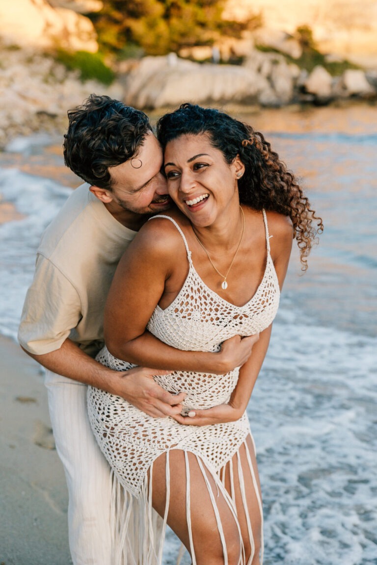couple riant pendant une séance photo grossesse en bord de mer