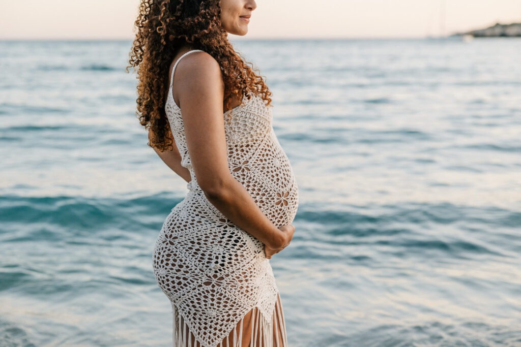 silhouette femme enceinte en robe crochet face à la mer pendant une séance grossesse