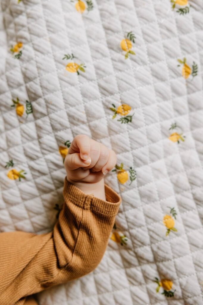 Détail de la main d’un bébé sur une couverture lors d’une séance photo naissance à domicile à Marseille