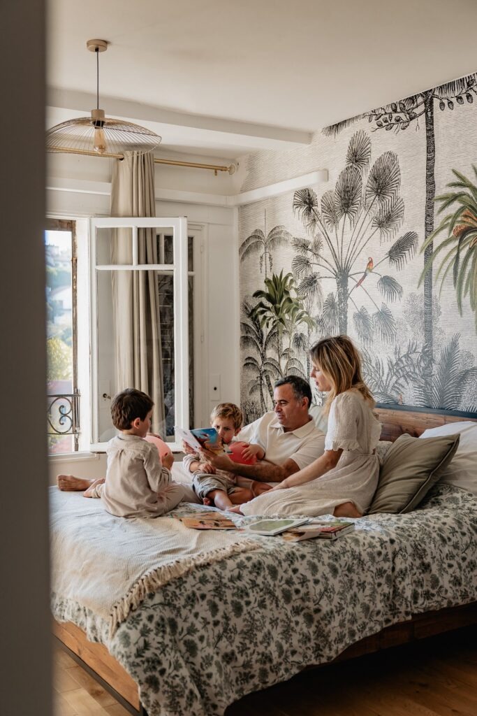 toute la petite famille lit un livre sur le lit des parents lors d'un shooting photo lifestyle de famille à domicile dans Marseille 13007