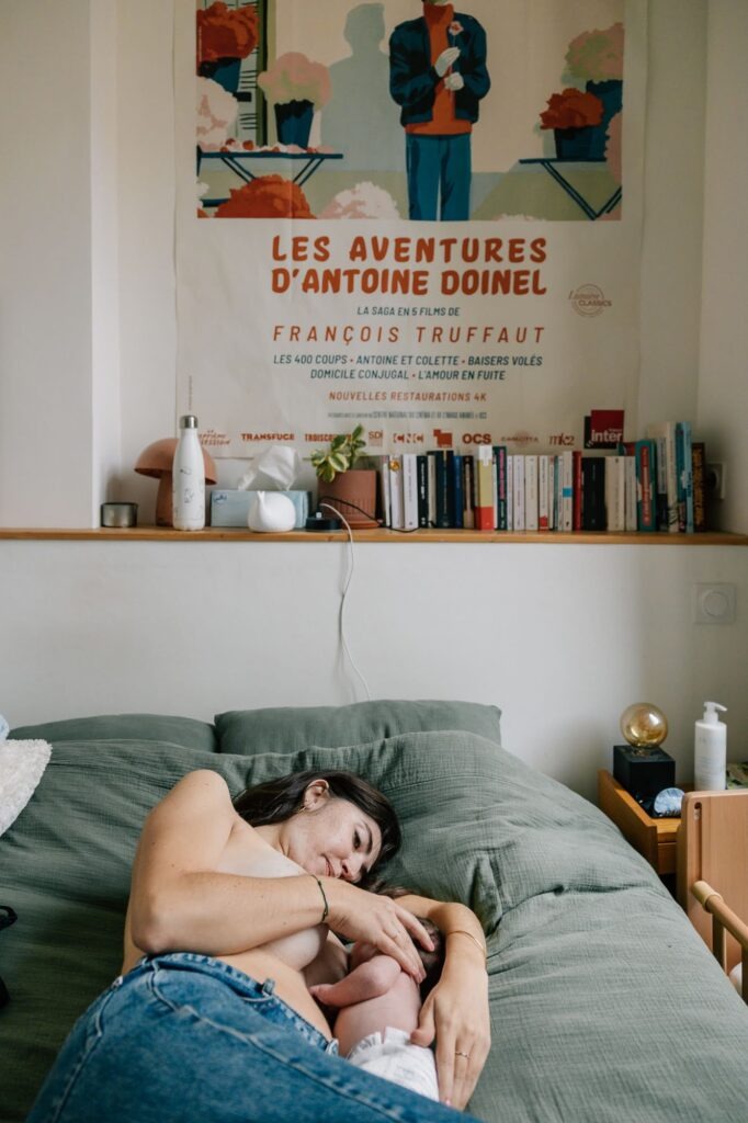 maman allongée sur le lit allaite son bébé nouveau-né séance photo naissance à domicile