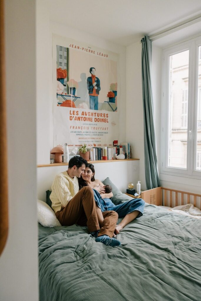 parents assis sur le lit avec leur bébé nouveau-né séance photo famille à domicile Marseille