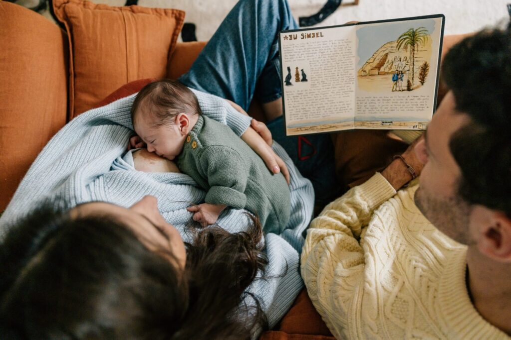 parents avec leur bébé nouveau-né sur le canapé séance photo famille à domicile