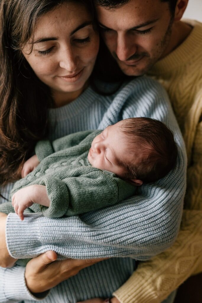 parents regardant leur bébé nouveau-né près de la fenêtre séance photo famille Marseille